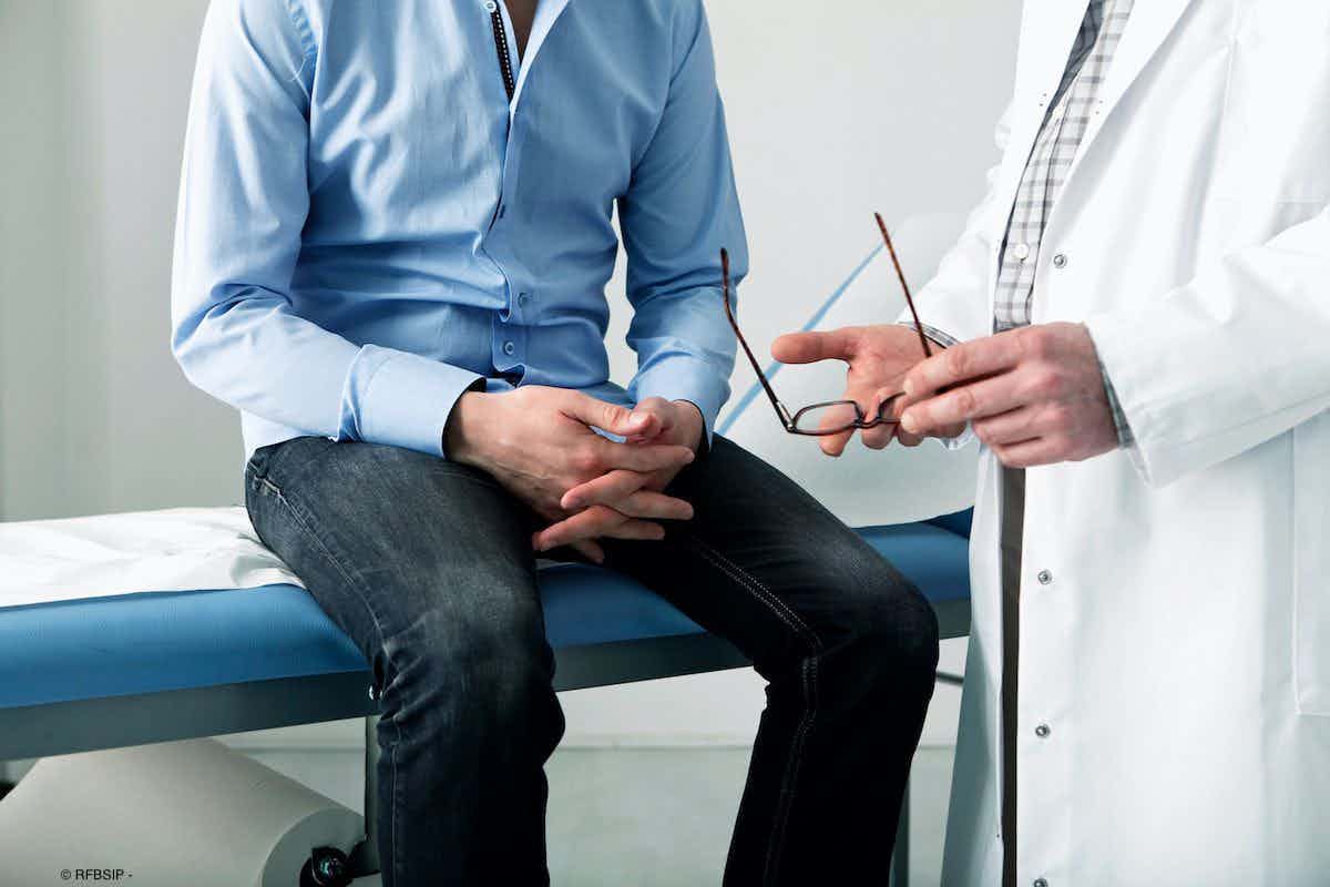 male patient sitting in clinic room while doctor talks with him 